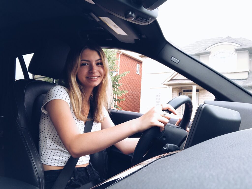 Happy young teenage girl smiling while taking her first driving lessons