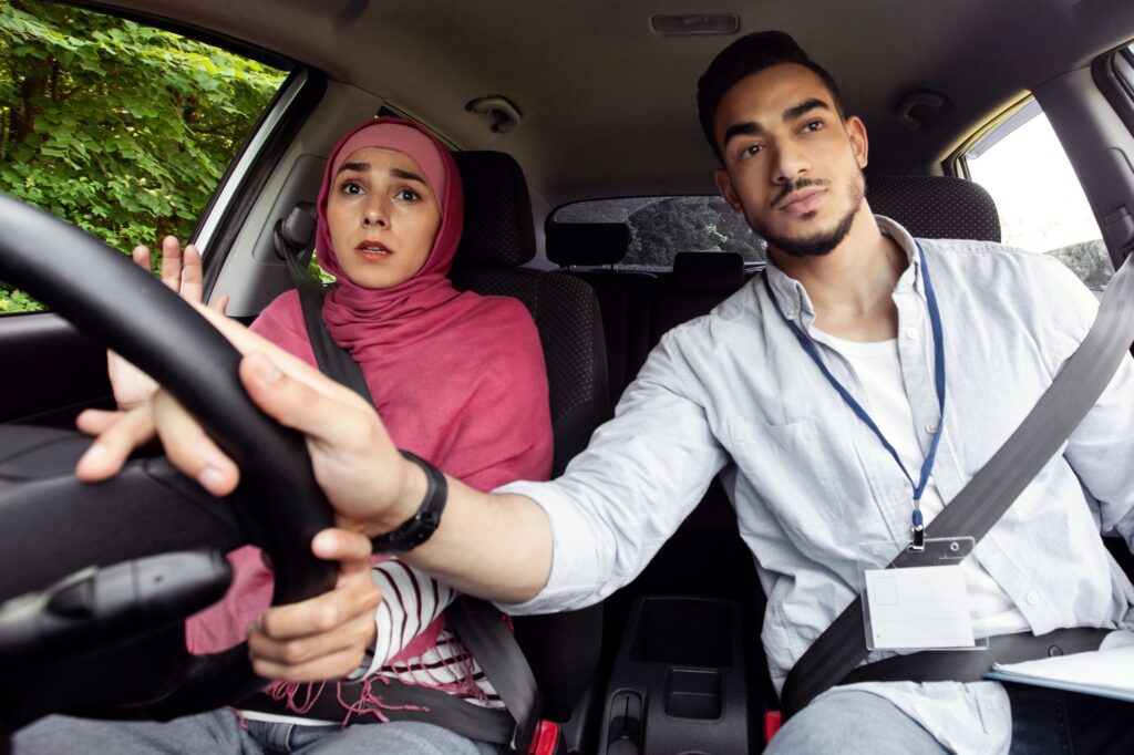 Nervous Muslim Lady In Hijab Having Driving Lesson With Instructor