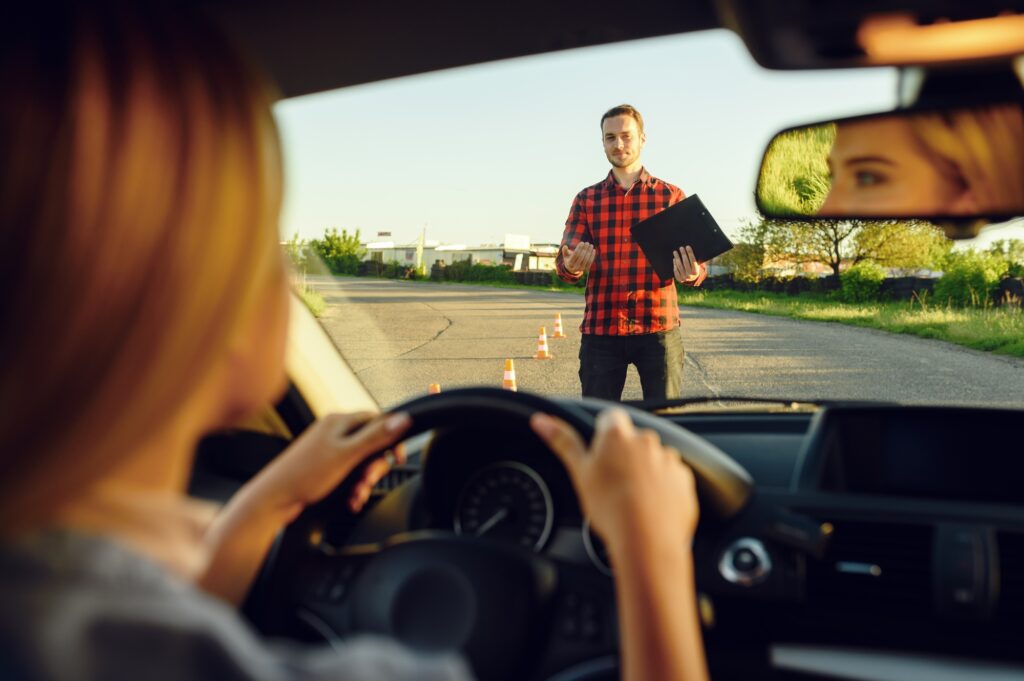 Woman in car, instructor with checklist on road