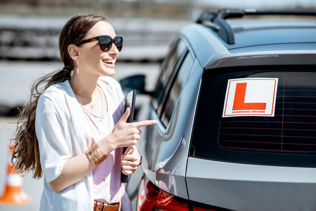 Woman near the learning car at the drivers school