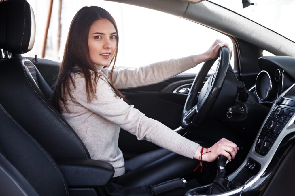 Young beautiful happy woman sitting at the wheel new car.