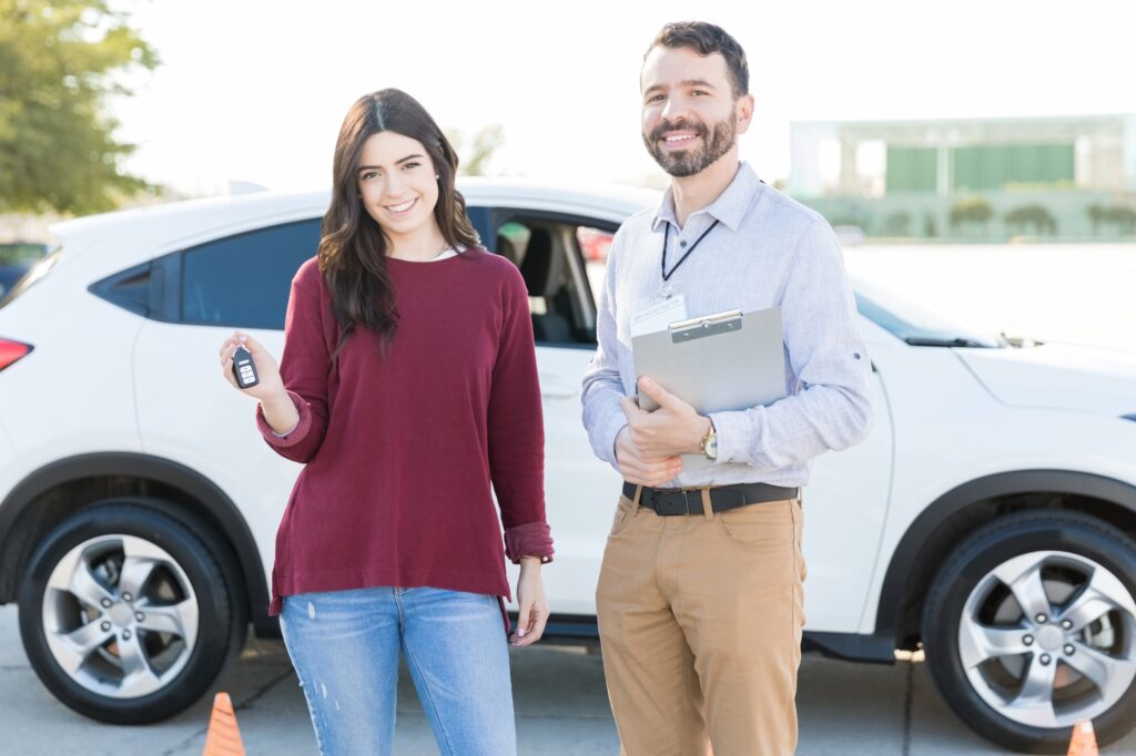 Confident Auto Teacher And Student Standing Against Car